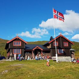 Mennesker samlet utenfor Silsethytta med det norske flagg i flaggstangen
