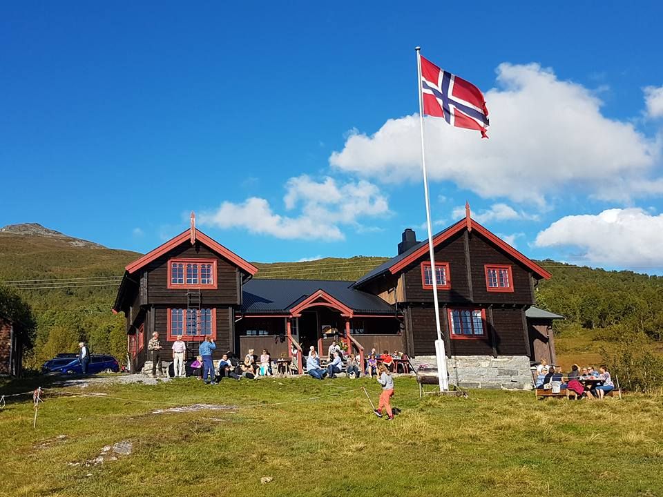 Mennesker samlet utenfor Silsethytta med det norske flagg i flaggstangen